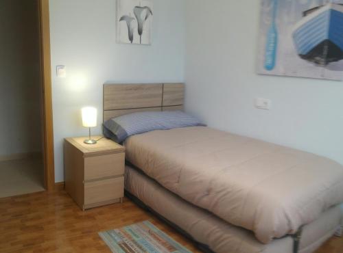 een slaapkamer met een bed en een nachtkastje met een lamp bij SMR As Pasadas in San Pedro de Benquerencia
