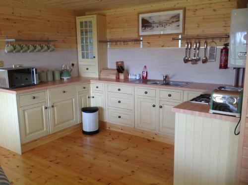 a kitchen with white cabinets and a counter top at Orme View Lodges in Bangor