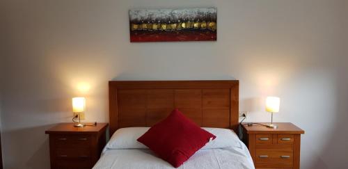 ein Schlafzimmer mit einem Bett mit einem roten Kissen und zwei Lampen in der Unterkunft Edificio Zoqueiro in San Cosme de Barreiros