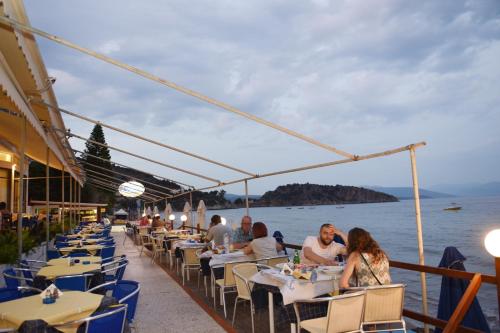 a group of people sitting at tables at a restaurant by the water at Hotel Solon in Tolo