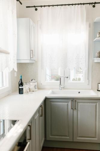 a kitchen with white cabinets and a window at Asterias house, Skopelos in Skopelos Town