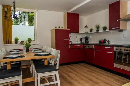 een keuken met een houten tafel en rode kasten bij Chaletparc Krabbenkreek Zeeland - Chalet 94 in Sint Annaland
