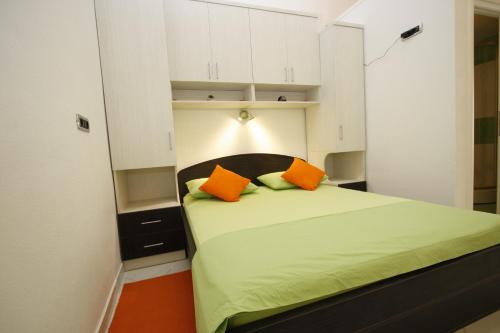 a small room with a bed with two orange pillows at Apartment Love Story in Makarska
