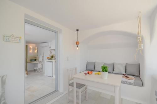 a white dining room with a white table and a mirror at Maroussa Studios in Agia Anna Naxos