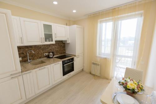 a kitchen with white cabinets and a sink and a window at Апартаменты Азбука Уфимский Кремль in Ufa