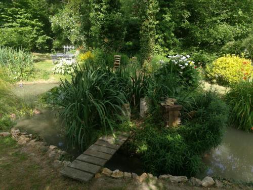 a garden with a bridge over a pond with plants at Le Clos du Buisson in Saint-Julien-de-la-Liègue