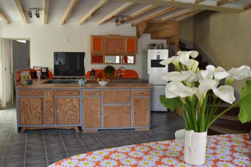 eine Küche mit Holzschränken und einer Vase aus weißen Blumen in der Unterkunft l'heureux bazar in Saint-Nectaire
