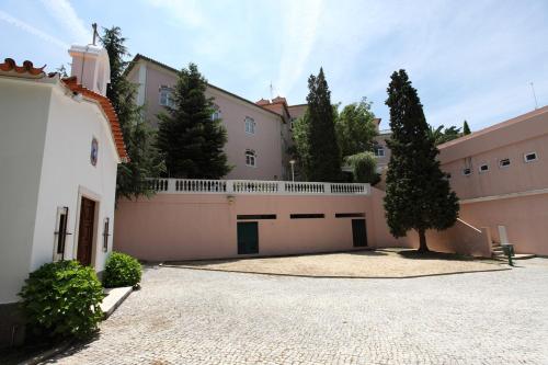 a courtyard of a building with a fence and trees at INATEL Luso in Luso
