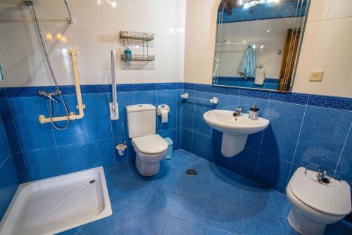 Un baño con azulejos azules, inodoro y lavabo. en Casa de Aldea el Ferreirón, en Castropol