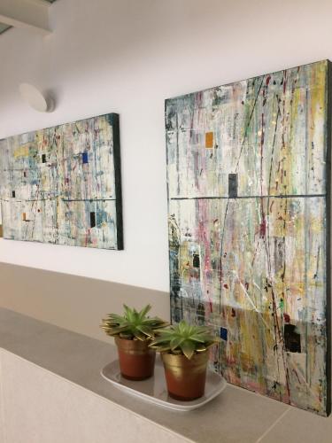 two potted plants in front of two paintings on a wall at LAMIA MATERA 11 in Matera