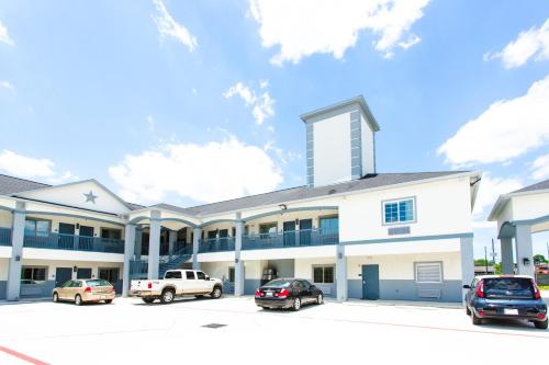 a white building with cars parked in a parking lot at Palace Inn- Louetta in Spring