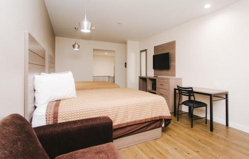 a hotel room with a bed and a desk and a chair at Palace Inn- Louetta in Spring