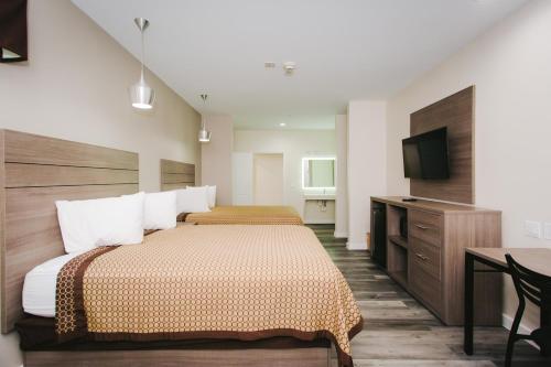 a hotel room with two beds and a flat screen tv at Palace Inn- Louetta in Spring