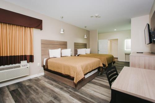 a hotel room with two beds and a television at Palace Inn- Louetta in Spring