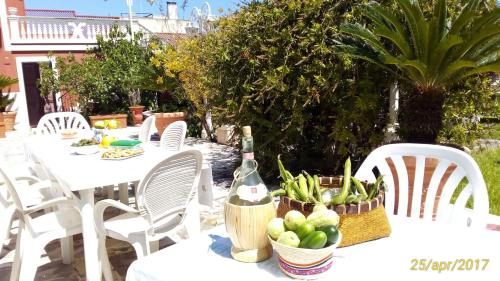 Villa Ida in Bari في باري: طاولة مع كراسي بيضاء وزجاجة من النبيذ