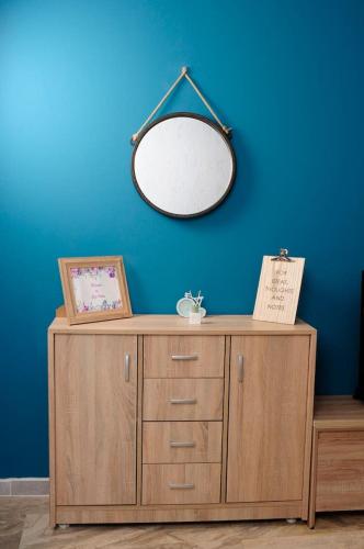 a mirror on top of a wooden cabinet against a blue wall at JOY'S HOME in Kalamata