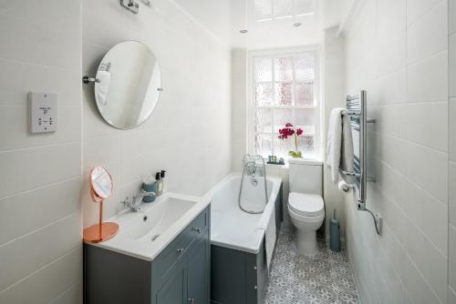 ein Badezimmer mit einem Waschbecken, einem WC und einem Spiegel in der Unterkunft Homm - Hyde park 2 bedroom flat in London