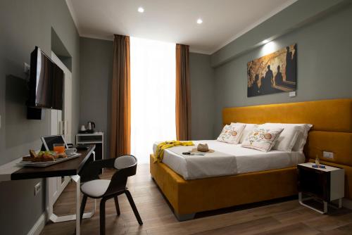 una camera d'albergo con letto, tavolo e scrivania di Dante Maison De Luxe a Napoli