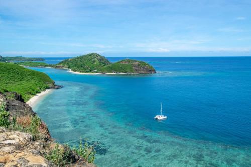 a boat in the water next to a beach at Barefoot Manta Island Resort in Drawaqa Island