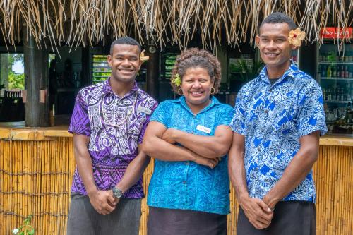 two men and a woman standing in front of a bar at Barefoot Manta Island Resort in Drawaqa Island