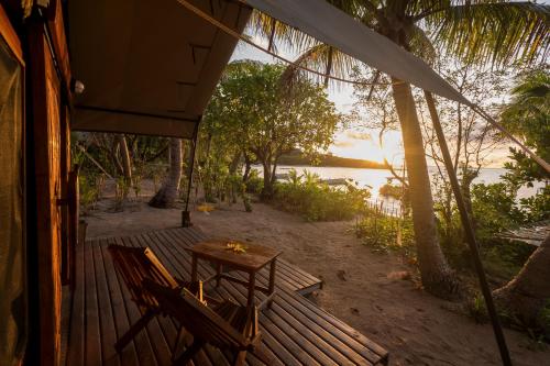 a wooden deck with a table and chairs on the beach at Barefoot Manta Island Resort in Drawaqa Island