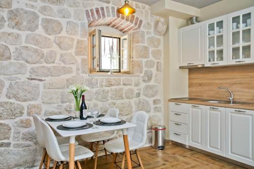 eine Küche mit einem Tisch, Stühlen und einer Steinmauer in der Unterkunft Vila Maestral Kotor in Kotor