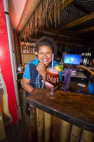 a woman sitting at a bar with a drink at Barefoot Manta Island Resort in Drawaqa Island