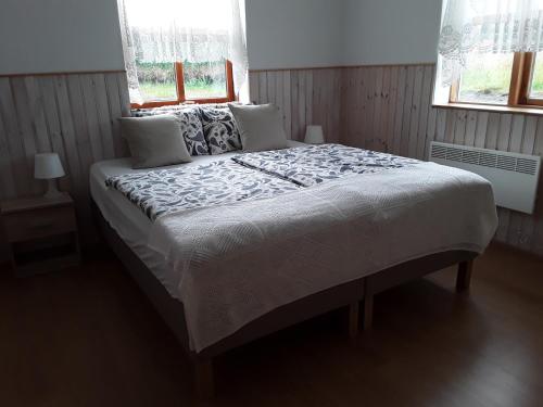 a large bed in a bedroom with two windows at Guesthouse Vestri-Gardsauki in Hvolsvöllur