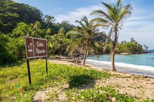 a sign on the side of a beach with palm trees at Casa Hotel La Mariela in Sapzurro