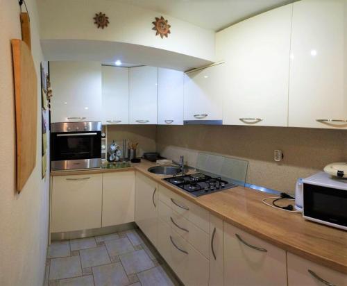a kitchen with white cabinets and a stove top oven at Traditional Dalmatian House Tina in Trogir