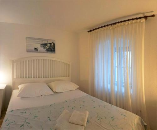 1 cama blanca con 2 almohadas y ventana en Traditional Dalmatian House Tina, en Trogir