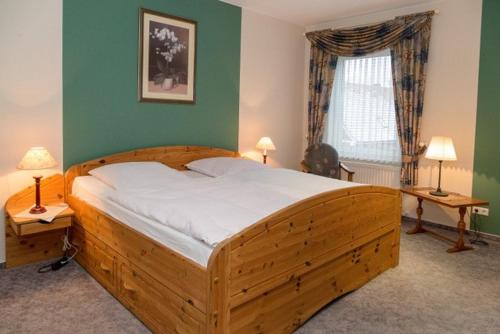 a large wooden bed in a bedroom with green walls at Gasthof Runge in Barenburg