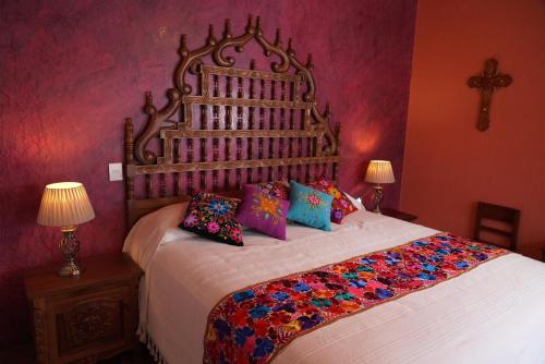 a bedroom with a large bed with colorful pillows at CASA ALFAREROS in Guadalajara