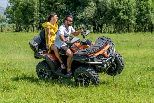 a man and woman riding on atvs in a field at Wooden Village Resort in Ponari