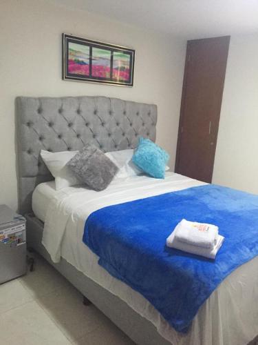 a bedroom with a large bed with blue sheets and pillows at Hotel Atardecer Guajiro in Ríohacha