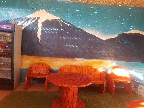 a table and two chairs in front of a mountain mural at Hostal Nuevo Sol y Viento in San Pedro de Atacama