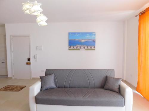 a white living room with a gray couch at Paradise in Għajnsielem