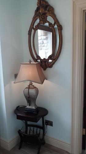 a lamp on a table in front of a mirror at Swallows Cottage in Swinford