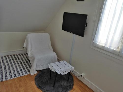 a room with a chair and a flat screen tv at Chambres d'Hôtes Chez Marilou in Aulnay-sous-Bois