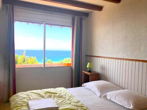 een slaapkamer met een raam met uitzicht op de oceaan bij Residence du valinco Appartement in Olmeto