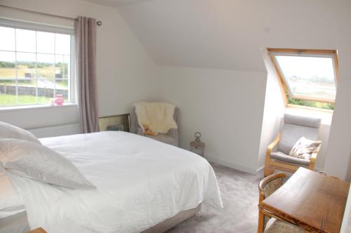 1 dormitorio con cama, ventana y silla en The Little Flock Farm en Cloonmore