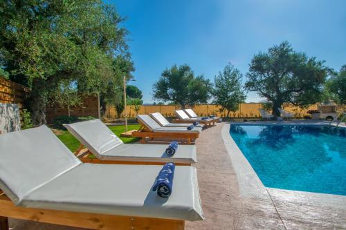 a row of lounge chairs next to a swimming pool at Zante Lagos holiday homes Treehouse and Villa in Vouyiáton