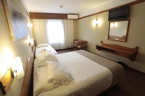 a hotel room with a bed and a mirror at Tri Hotel in Canela