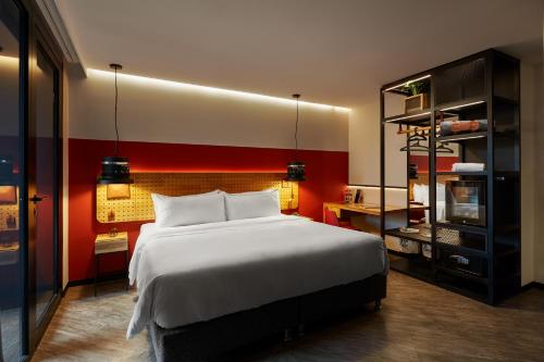 ein Schlafzimmer mit einem großen Bett und einer roten Wand in der Unterkunft The Click Clack Hotel Medellín in Medellín