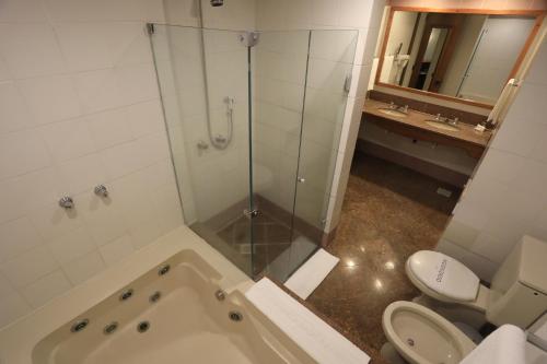 a bathroom with a shower and a toilet and a tub at Tri Hotel in Canela