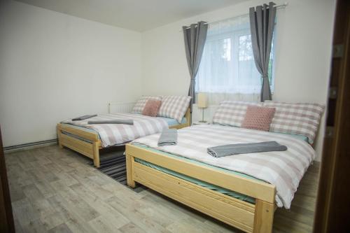two twin beds in a room with a window at Apartmány Ve Mlejně in Čachrov
