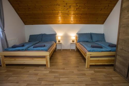 two beds in a room with a wooden ceiling at Apartmány Ve Mlejně in Čachrov