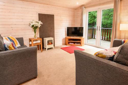 a living room with two couches and a flat screen tv at Woodlands Hotel & Pine Lodges in Grange Over Sands