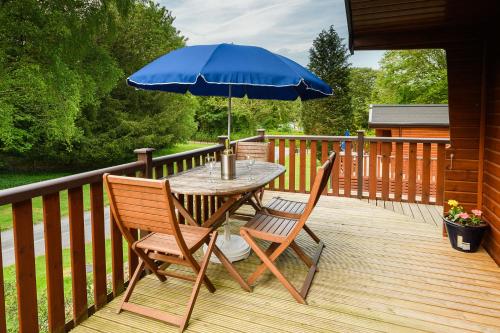 a table and two chairs with an umbrella on a deck at Woodlands Hotel & Pine Lodges in Grange Over Sands