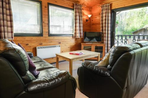 a living room with two leather couches and a table at Woodlands Hotel & Pine Lodges in Grange Over Sands